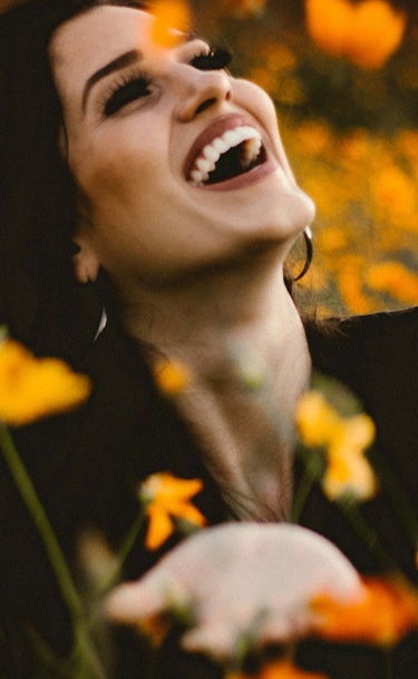 Signature Dental Aesthetics woman smiling in field with flowers mobile